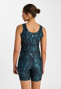 Ensemble débardeur et short de sport en bleu foncé avec un motif fluide et ondulé. Présente une coupe ajustée et des détails de logo blancs au dos.