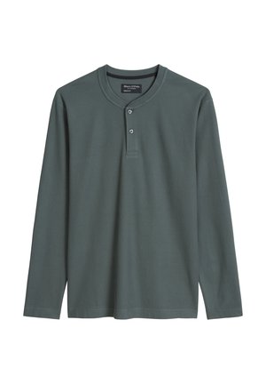 Langärmliges Henley-Shirt aus dunkelgrünem, geripptem Stoff. Es hat einen abgerundeten Halsausschnitt, zwei Knöpfe am Brustbereich und seitliche Schlitze am Saum.