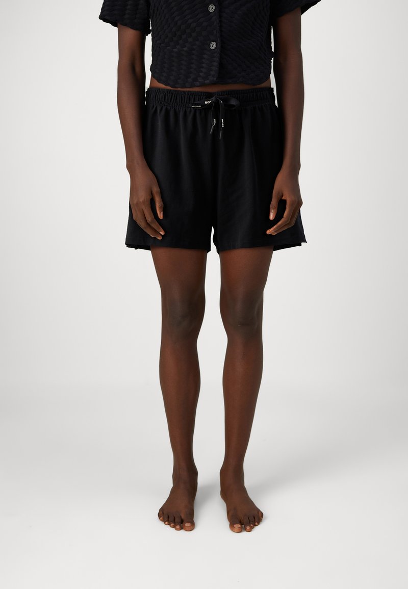 Zwarte, lichte shorts met een elastische tailleband en koord. Heeft een relaxte pasvorm en komt tot boven de knie. Soepele textuur.