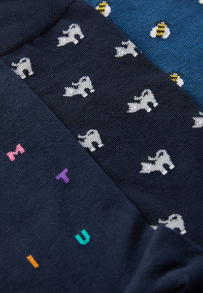 Tre paia di calzini con sfondo blu scuro. Un paio presenta motivi di animali bianchi, un altro ha motivi di api e accenti di testo colorati.