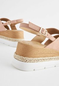 Sandale cu platformă din suede roz deschis, cu un design cu curele încrucișate, wedge cu textură de lemn și talpă din cauciuc albă, accentuate de iută țesută.
