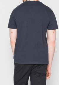 Námořnická modrá bavlněná tričko s krátkými rukávy a kulatým výstřihem, s rovnými lemy a minimálními švy.