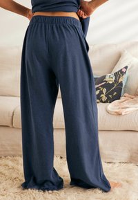 Pantaloni a gamba larga blu navy realizzati in tessuto morbido con vita elasticizzata, che presentano una silhouette rilassata e fluida.