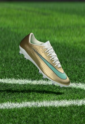 Guld- og hvid fodboldstøvle med teal swoosh svæver over grøn græs nær hvide marklinjer.