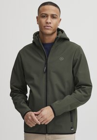 Dark green jacket with a hood, made from smooth material. Features a front zipper and a circular logo on the chest, with black trim accents.