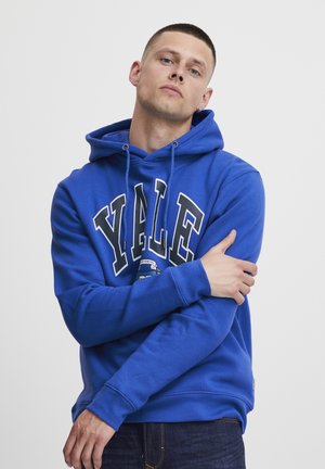 Modrá mikina s kapucňou vyrobená z bavlny s šnúrkou na kapucni. Na prednej strane je vytištené "YALE" bielou farbou, spolu s grafickým logom.