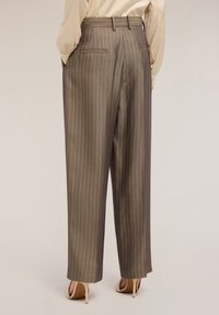 Kalhoty s vysokým pasem, hnědé pruhované, se širokými nohavicemi, obsahující dvě zadní kapsy a hladký povrch, v kombinaci s béžovými podpatky.