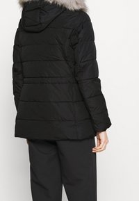 Sort pufferjakke med aftagelig faux fur hætte, quiltet design og lange ærmer. Kantlinjen er lige, og materialet har en glat tekstur.