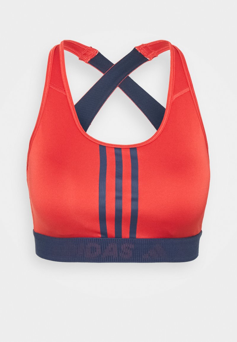 Soutien-gorge de sport rouge avec des bretelles croisées bleu marine. Présente des rayures bleu marine au centre et une bande bleu marine avec un logo en bas. Texture lisse.
