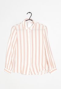 Chemise blanche à manches longues avec des rayures horizontales roses, col classique, fermeture par boutons, et ourlet légèrement arrondi. Tissu léger.