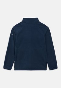 Tamsiai mėlynas flisinis megztinis su aukštu kaklu, raglaninėmis rankovėmis ir lygiu paviršiumi. Kairėje peties pusėje yra mažas logotipas.