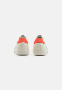 Ténis Skechers com parte superior em creme, painel lateral em aqua e etiqueta de calcanhar em coral neon. Material suave e design minimalista de perfil baixo.
