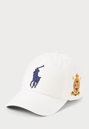 Fehér, pamut baseball sapka, melyen egy sötétkék hímzett póló játékos logo található, valamint egy arany és piros címer az oldalon.