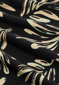 Tessuto nero con una trama testurizzata, caratterizzato da un motivo di foglie in menta e beige. Il design ha una qualità tattile in rilievo.