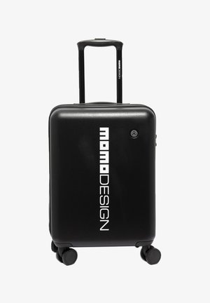 Zwarte harde handbagagekoffer met vier wielen, uitschuifbare handgreep en verticale witte "momoDESIGN"-logo aan de voorkant.