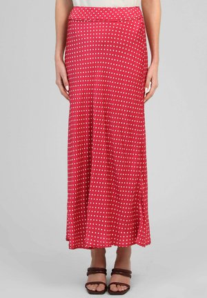 Jupe midi rouge à pois blancs, portée avec des sandales marron à brides, montrée de la taille aux pieds sur un fond uni.