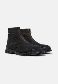 Botas de tobillo negras con un upper de tejido acanalado, que cuentan con dobles cremalleras y una suela de goma texturizada con relieves para un mejor agarre.