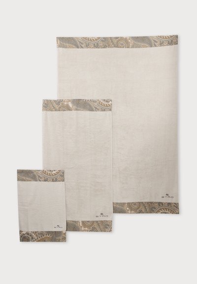 Trois serviettes beiges de tailles différentes avec des bordures à motif paisley en marron et gris, empilées de la plus petite à la plus grande sur un fond blanc.