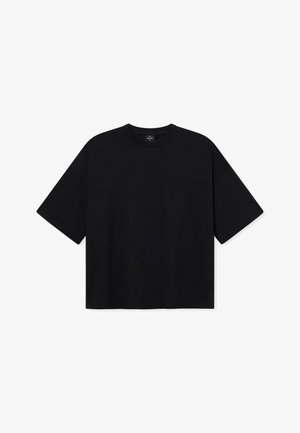 Fekete, oversize póló sima anyagból, kerek nyakkal és rövid ujjal, világoskék farmernadrággal viselve.