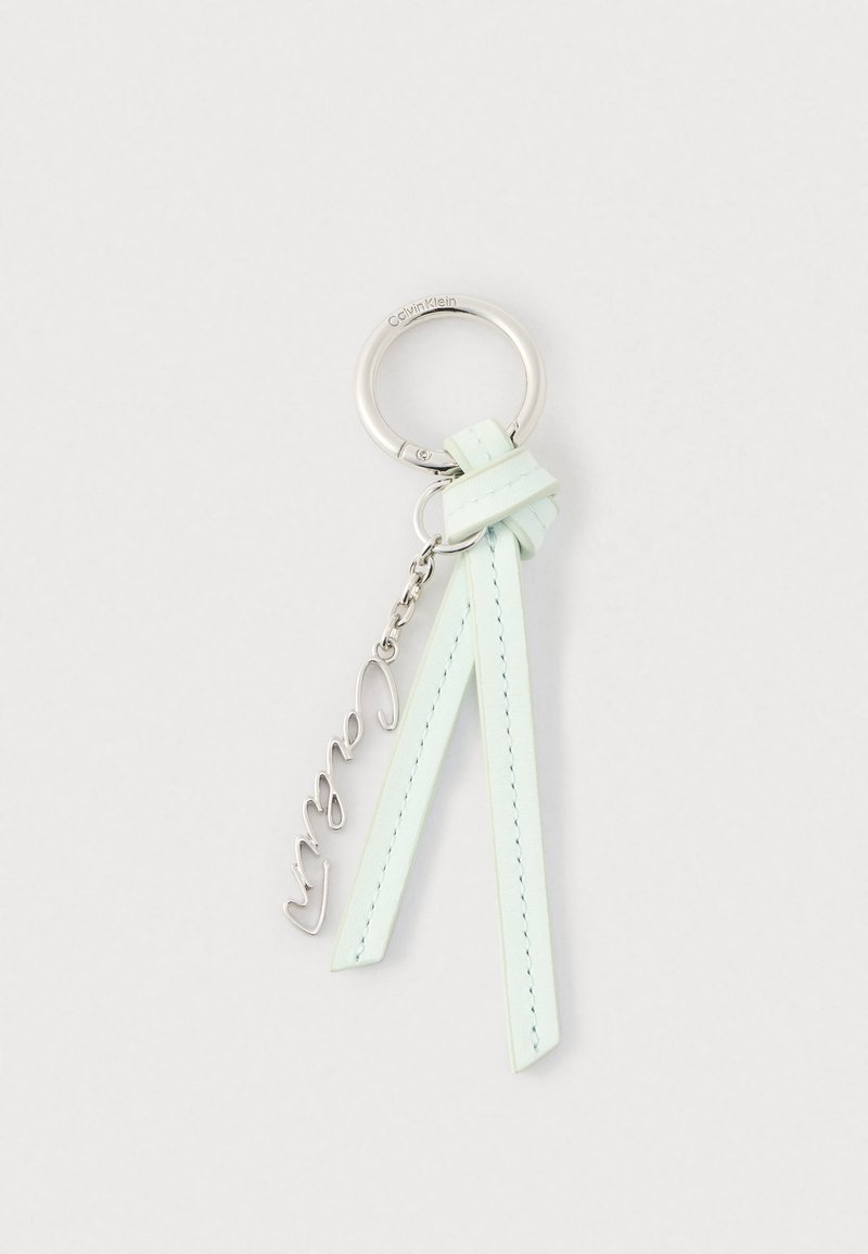 Porte-clés anneau argenté Calvin Klein avec deux lanières en cuir vert menthe pâle et un pendentif métallique en forme de mot "love" en cursive, sur fond blanc.