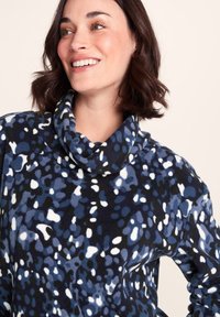 Cowl-neck fleece top featuring a splatter pattern in shades of blue, black, and white. Soft texture with a relaxed fit design.