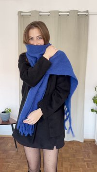 Blå uldne tørklæde om skuldrene med frynser. Sort tekstureret outfit og prikkede tights komplementerer tilbehøret. Indendørs miljø.