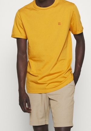 Żółta bawełniana koszulka z okrągłym dekoltem i podwiniętymi rękawami, z małym czerwonym haftem "II" na piersi.