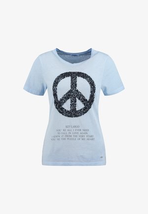 Maglietta azzurra a maniche corte con simbolo della pace in paillettes nere e testo stampato con la scritta "KEY LARGO" e una poesia a tema amore sotto.