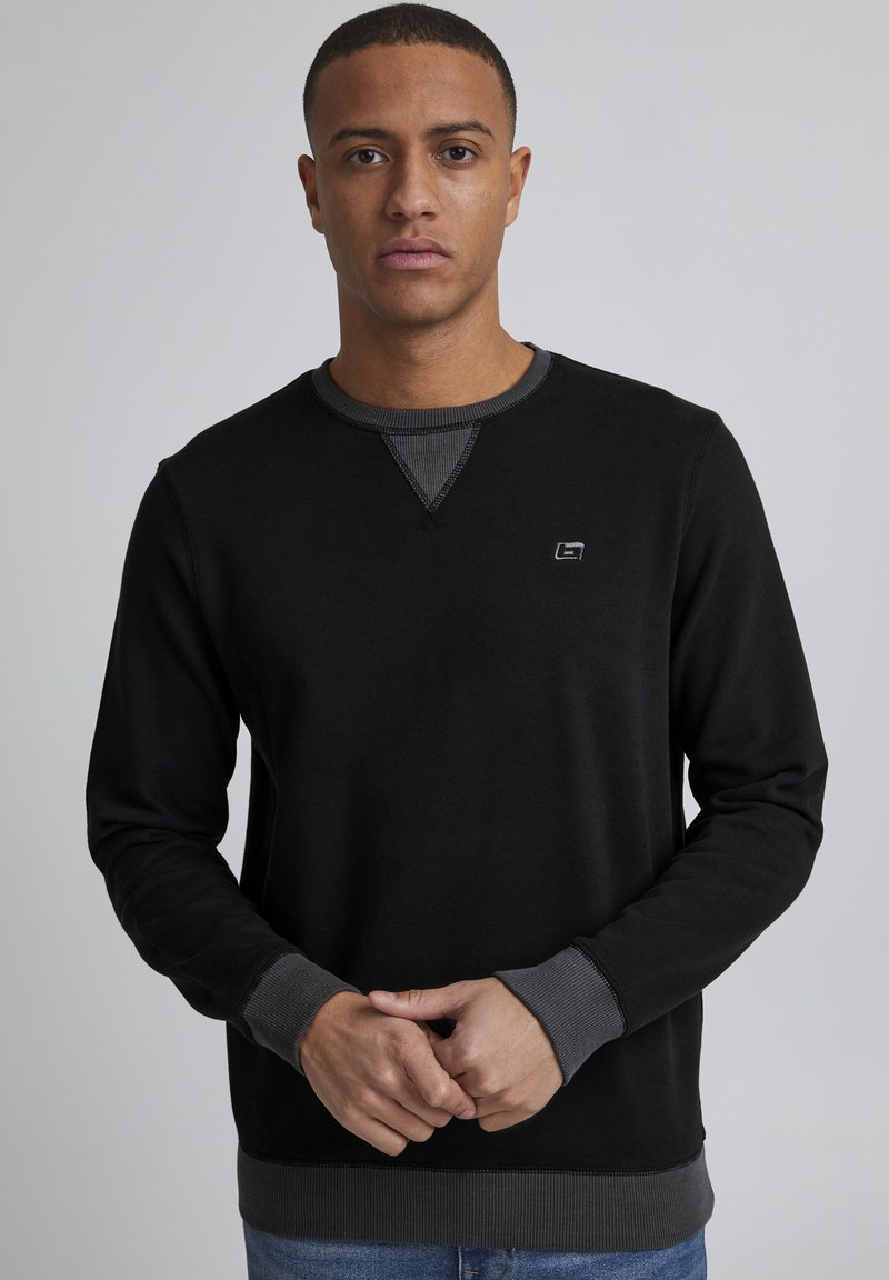 Schwarzer Sweatshirt mit langen Ärmeln, Rundhalsausschnitt und kontrastierenden grauen Rippbündchen sowie Saum. Verfügt über ein kleines Logo auf der Brust.