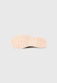 Suela de zapato de goma en rosa pálido con textura en el dibujo, que presenta surcos y patrones para mejorar el agarre, diseñada para la durabilidad y la tracción.