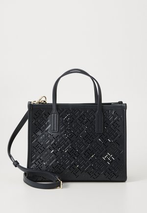 Navy perforierte Leder-Handtasche mit doppelten oberen Traggriffen, abnehmbaren Schulterriemen und geometrischem Ausschnittmuster auf der Vorderseite.