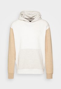Sweat à capuche blanc avec manches longues beige, poche kangourou à l'avant et logo discret sur la poitrine sur un fond uni.