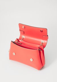 Coral leather handbag with a smooth texture, two compartments, gold hardware, and snap closure. Interior features a zippered pocket.