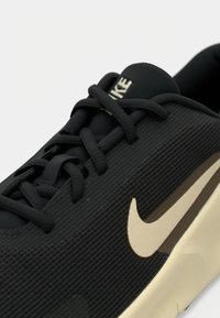 Μαύρο αθλητικό παπούτσι με υφασμένο πάνω μέρος, εμφανές σύστημα κορδονιών και μπεζ λογότυπο Nike στο πλάι.