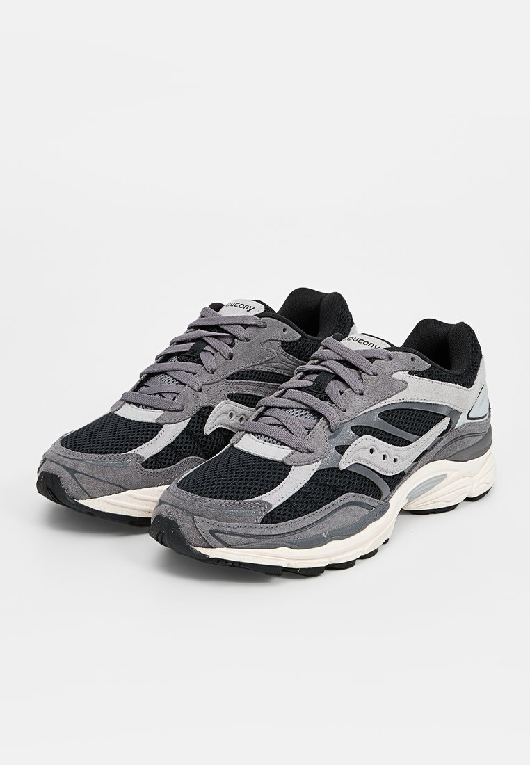 Une paire de chaussures de course Saucony noires et grises avec des panneaux en maille et en daim, des semelles intermédiaires blanches et des lacets gris sur un fond blanc.