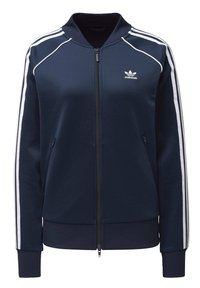 Námořnická modrá sportovní bunda Adidas se bílými pruhy podél rukávů, zipem vpředu, zipovými bočními kapsami a žebrovaným límcem, manžetami a spodním lemem.