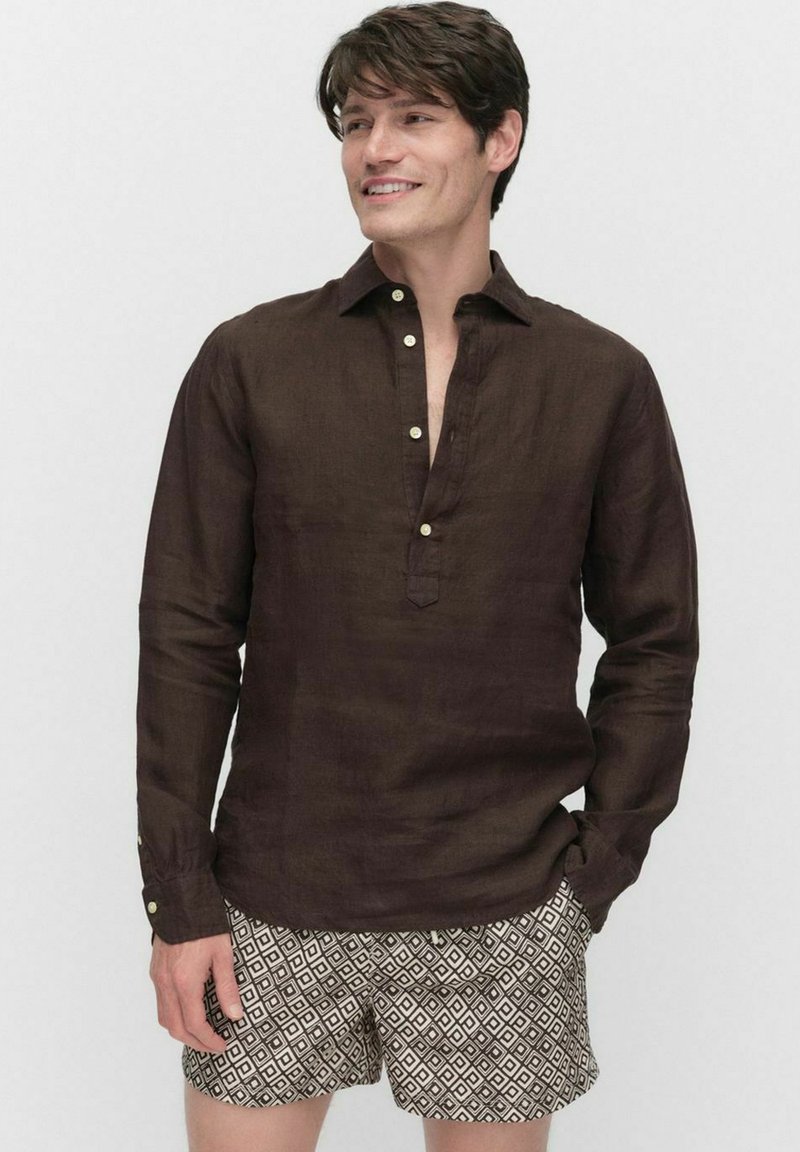 Chemise en lin marron à manches longues avec patte de boutonnage partielle, associée à un short beige à motifs avec des designs géométriques.