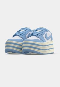 Μπλε και λευκά αθλητικά παπούτσια με χοντρή, πολυεπίπεδη σόλα. Κατασκευασμένα από δέρμα και δίχτυ, με διάτρητο κουτί δαχτύλων και επίπεδα κορδόνια.