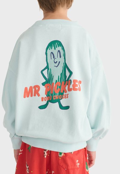 Enfant portant un sweat-shirt bleu clair avec un personnage cartoon de cornichon et un texte rouge « MR PICKLES 2020 CHOSES » dans le dos, assorti à un short rouge.