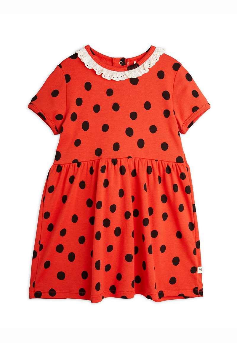 Robe rouge à manches courtes avec des pois noirs, une jupe froncée et un col blanc orné de dentelle. Comprend une fermeture à boutons au dos.