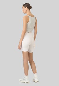 Szary krótki top, białe szorty o wysokim stanie, sportowe buty z teksturowaną podeszwą. Prosty design; dopasowany krój podkreśla sylwetkę.