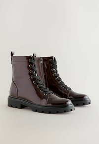 Botas de tobillo con cordones en cuero sintético burdeos, con cordones negros, una cremallera lateral y una suela de goma gruesa con un profundo dibujo.