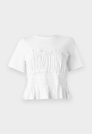 Balta īsām piedurknēm topiņš ar rievotu, smockotu torso un izpletu apakšmalu, kas izceļ teksturētu dizainu un vienkrāsainu krāsu.