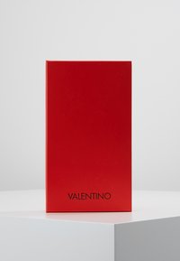 Red packaging box with a glossy finish. Black "VALENTINO" logo at the bottom. Rectangle shape, smooth texture, no additional designs or accents.