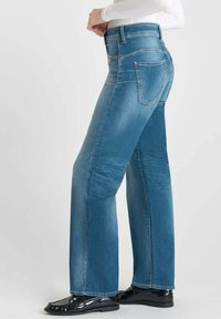 Jeans dritti di colore blu chiaro in denim. Caratterizzati da cinque tasche, dettagli in oro e una leggera scoloritura sulle gambe.