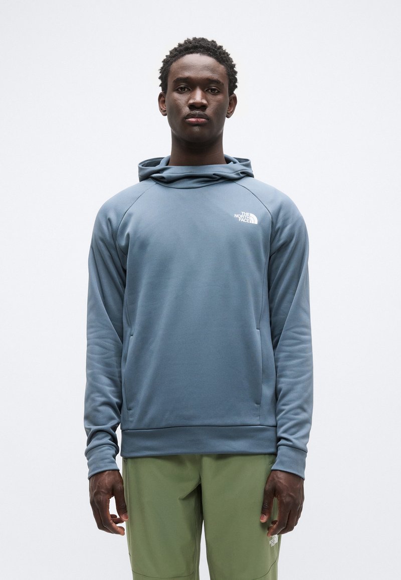 Φωτεινή γαλάζια φούτερ με κουκούλα από υφασμάτινη υφή, με μπροστινή τσέπη και κουκούλα. Διαθέτει λευκό λογότυπο στο πάνω αριστερό μέρος. Συνδυάζεται με πράσινο παντελόνι.