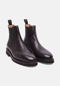 Bottes Chelsea en cuir marron avec des panneaux latéraux élastiques, une finition texturée, un bout pointu et une semelle épaisse et robuste pour une bonne adhérence.