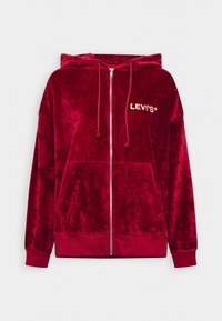 Felpa rossa in velluto con zip, con coulisse, tasche a marsupio e logo "LEVI'S" ricamato in oro. Tessuto morbido e vestibilità rilassata.