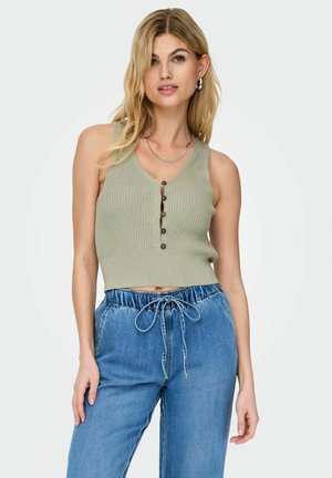 Top sin mangas de canalé verde claro con escote en V y cierre de cinco botones, combinado con pantalones de denim holgados con un cordón ajustable.