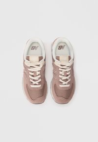 Pink fabric sneakers with cream laces, cushioned insoles, and a textured upper. Features a logo on the tongue and a rubber sole.